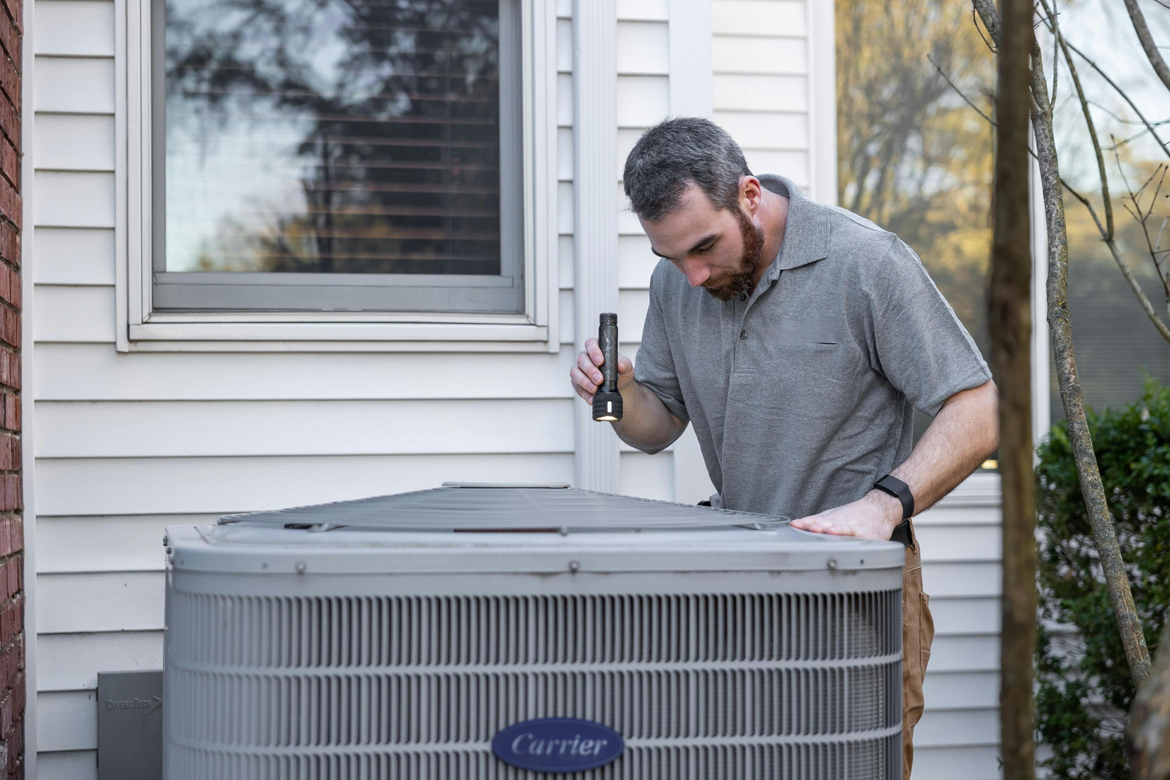 HVAC technician inspecting outdoor AC unit at a Gresham OR home